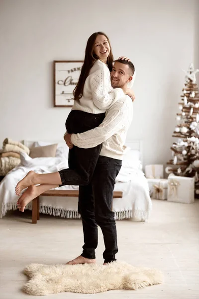 Adam karısını parlak ve şık bir Noel süsüsüyle parlak bir odada büyütüyor.. — Stok fotoğraf