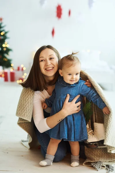 Weihnachtlicher Hintergrund. Porträt einer glücklichen Mutter und ihrer Tochter, die Spaß haben und in eine Decke gehüllt sind. — Stockfoto