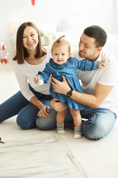 Feliz mamá papá y su hija jugando sentado en el suelo en la sala de estar en la mañana de Navidad. — Foto de Stock