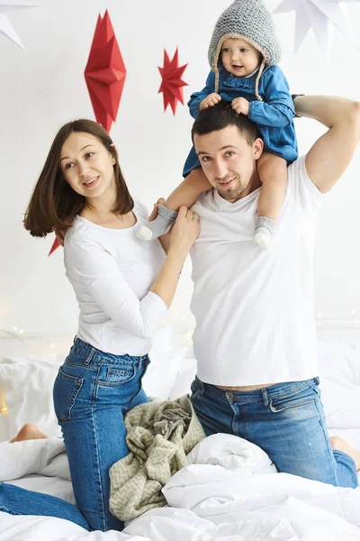 Lycklig mamma pappa och dotter leker på sängen i sovrummet på juldagsmorgonen. — Stockfoto