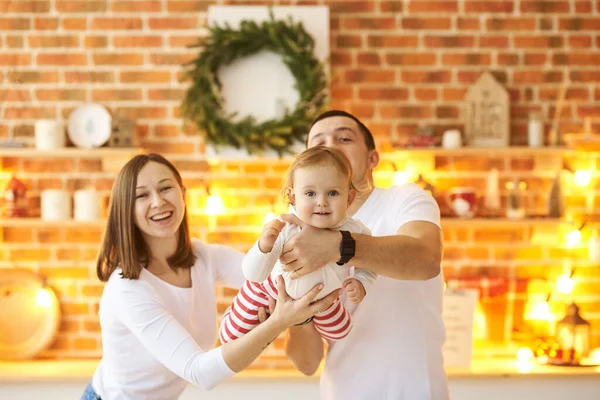 Junge Familie mit kleinem Kind genießt Weihnachten zu Hause in einem gemütlichen, hellen Zimmer. — Stockfoto