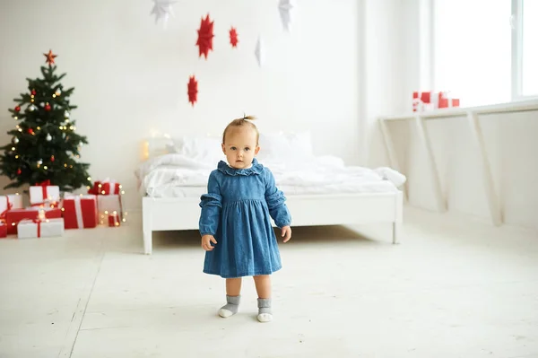 Mavi kot elbise giymiş, parlak bir odada duran küçük bir kızın portresi.. — Stok fotoğraf
