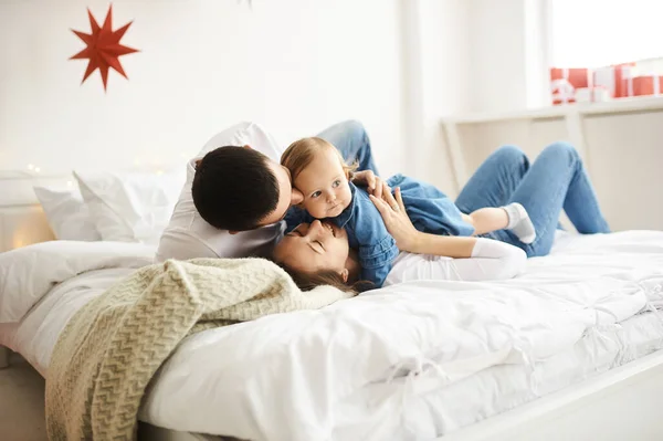 Lycklig mamma pappa och dotter leker på sängen i sovrummet på juldagsmorgonen. — Stockfoto