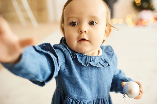 Porträt eines kleinen Mädchens in einem blauen Jeanskleid, das in einem hellen Raum steht. — Stockfoto