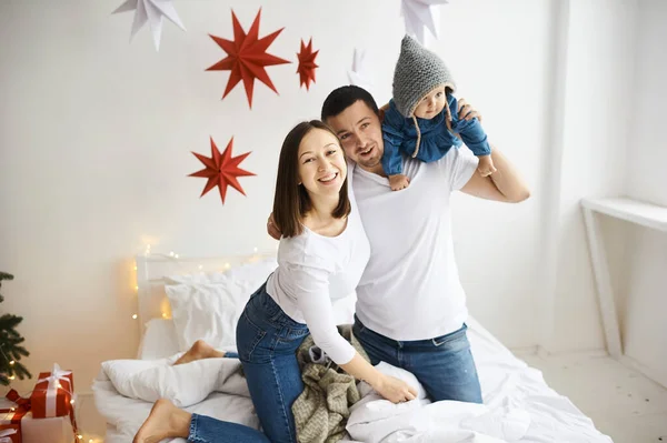 Glücklich mutter papa und tochter spielend auf das bett im schlafzimmer am weihnachtsmorgen. — Stockfoto