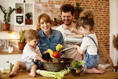 Çocukları mutfakta yemek yaparken mutlu bir aile.