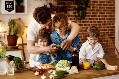 Çocukları mutfakta yemek yaparken mutlu bir aile.