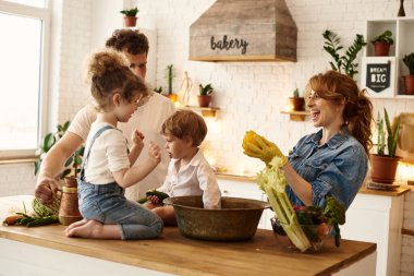 Çocukları mutfakta yemek yaparken mutlu bir aile.