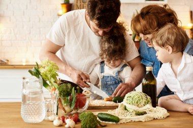 Çocukları mutfakta yemek yaparken mutlu bir aile.