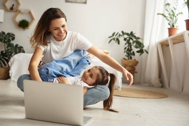 Anne bilgisayar başında çalışırken kız anne ve kediyle oynuyor.