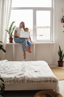 Anne bilgisayar başında çalışırken kız anne ve kediyle oynuyor.