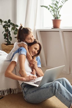 Anne bilgisayar başında çalışırken kız anne ve kediyle oynuyor.