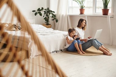 Anne bilgisayar başında çalışırken kız anne ve kediyle oynuyor.