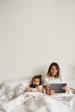 Anne bilgisayar başında çalışırken kız anne ve kediyle oynuyor.