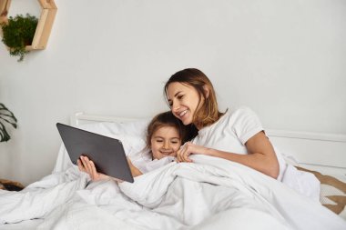 Anne bilgisayar başında çalışırken kız anne ve kediyle oynuyor.