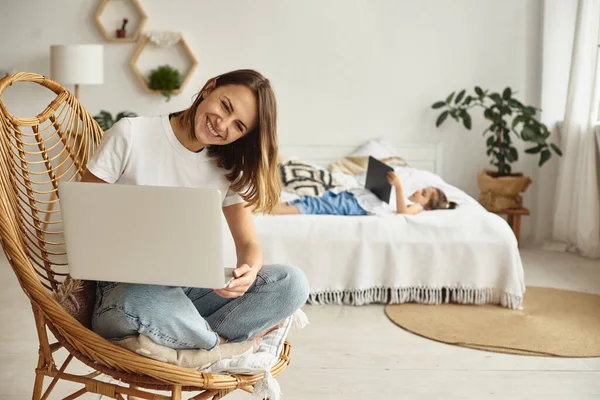Anne bilgisayar başında çalışırken kız anne ve kediyle oynuyor.