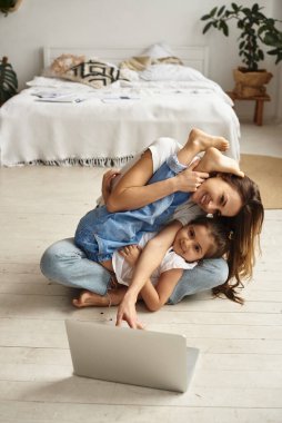 Anne bilgisayar başında çalışırken kız anne ve kediyle oynuyor.