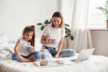 Anne bilgisayar başında çalışırken kız anne ve kediyle oynuyor.