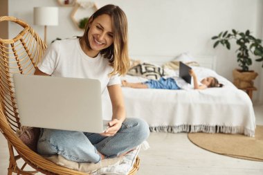 Anne bilgisayar başında çalışırken kız anne ve kediyle oynuyor.