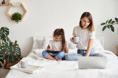 Anne bilgisayar başında çalışırken kız anne ve kediyle oynuyor.