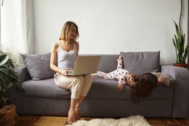 Anne bilgisayar başında çalışırken kız anne ve kediyle oynuyor.