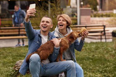 Köpekli genç çift fast food yiyor.