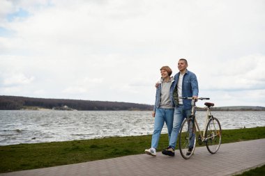 Genç bir çift gölün kenarında bisiklet sürüyor..