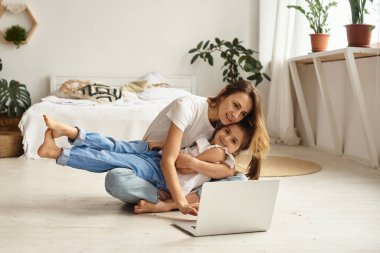 Anne bilgisayar başında çalışırken kız anne ve kediyle oynuyor.