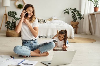 Anne bilgisayar başında çalışırken kız anne ve kediyle oynuyor.