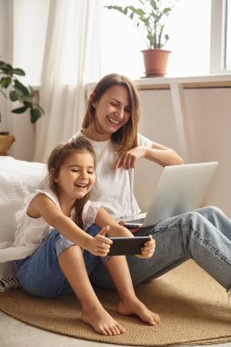 Anne bilgisayar başında çalışırken kız anne ve kediyle oynuyor.