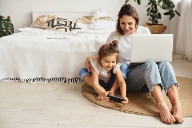 Anne bilgisayar başında çalışırken kız anne ve kediyle oynuyor.