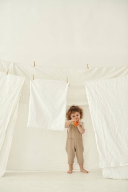 Beyaz bir odada elinde bir parça peynir tutan bir çocuk var..