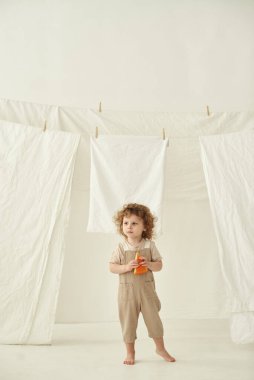 Beyaz bir odada elinde bir parça peynir tutan bir çocuk var..