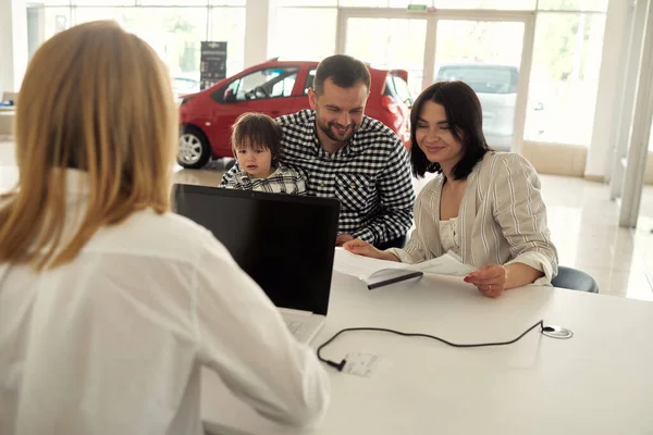 The manager helps the young family choose the most comfortable car for the city.