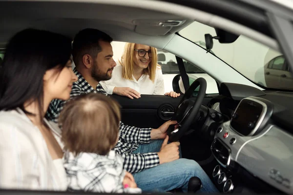 The manager helps the young family choose the most comfortable car for the city.