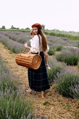 Anne ve kızı birlikte sepetteki lavanta çiçeklerini topluyorlar..