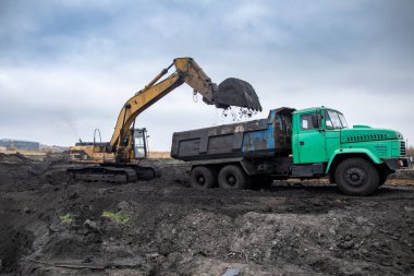 Dnipro, Ukrayna - 19 Kasım 2020: CAT sürüngen kazıcısı iş başında. Ham maddeler arabaya yükleniyor..