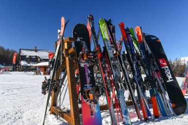 Sauze D 'Oulx, Torino, İtalya - 13 Ocak 2025: Sauze D' Oulx kayak merkezindeki bir restoranın dışındaki kayak ve snowboard 'lar. Bir kış sporları tesisinde dinleniyor, güneşte dinleniyor.