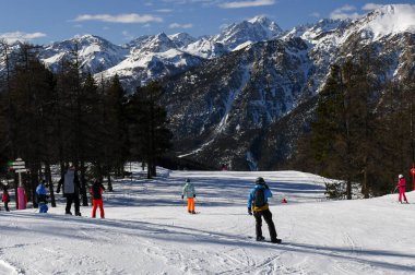 Montgenevre, Fransa - 17 Ocak 2025: Fransız kayak merkezi Montgenevre 'de kayak pistine inen kayakçılar ve snowboardcular. Provence-Alpes-Cte d 'Azur bölgesinde ağaçlı ve karlı kış dağları.