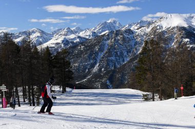Montgenevre, Fransa - 17 Ocak 2025: Fransız kayak merkezi Montgenevre 'de kayak pistine inen kayakçılar ve snowboardcular. Provence-Alpes-Cte d 'Azur bölgesinde ağaçlı ve karlı kış dağları.