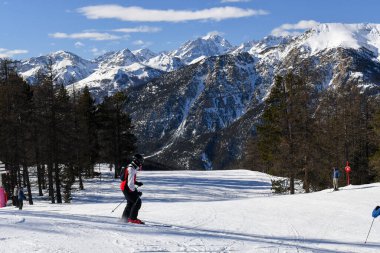 Montgenevre, Fransa - 17 Ocak 2025: Fransız kayak merkezi Montgenevre 'de kayak pistine inen kayakçılar ve snowboardcular. Provence-Alpes-Cte d 'Azur bölgesinde ağaçlı ve karlı kış dağları.