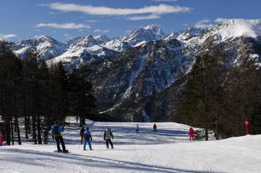 Fransız kayak merkezi Montgenevre 'de kayak ve snowboard yapan bir grup insan. Fransa 'nın Provence-Alpes-Cte d' Azur bölgesindeki güzel ağaçlı piste ve karlı kış dağlarına.