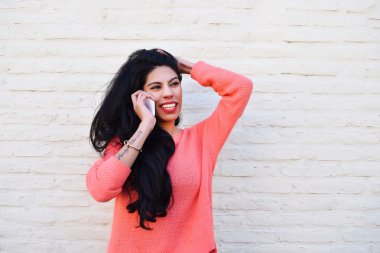 Genç Latin kadın telefonda konuşuyor.