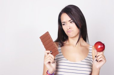 Genç kadın çikolata ya da elma yemek arasında karar verme