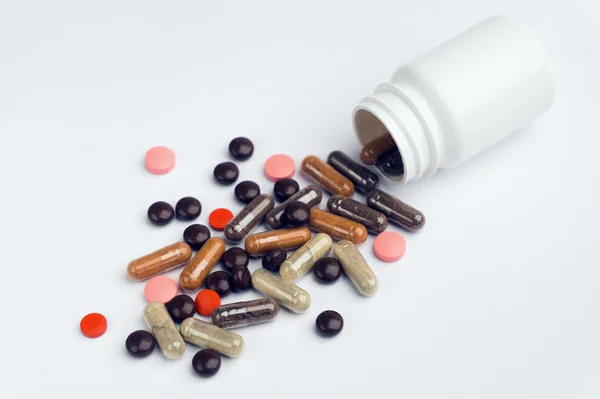 Diverse pillole e capsule sparse su uno sfondo bianco . — Foto Stock