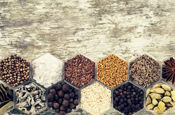 Spices in hexagonal jars on a wooden surface — Stock Photo, Image