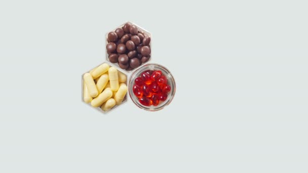 Várias pílulas e cápsulas em frascos hexagonais aparecem em um fundo cinza — Vídeo de Stock