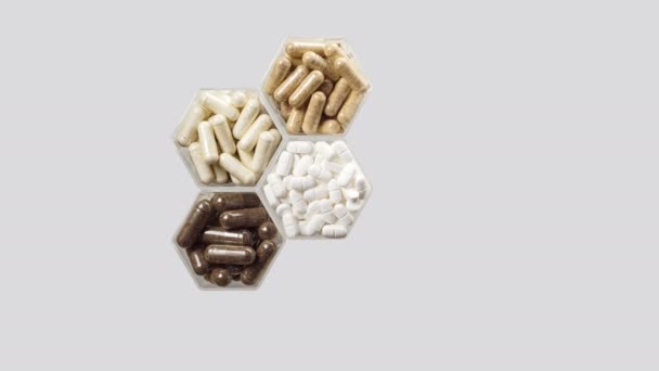 Varias píldoras y cápsulas en frascos hexagonales aparecen sobre un fondo gris — Vídeos de Stock