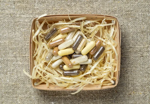 Herbal and mineral organic dietary supplements in capsules in a wooden box in the shape of a nest