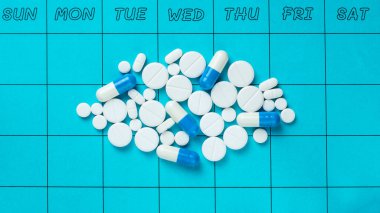 Pill schedule, various pills and capsules on a weekly calendar clipart